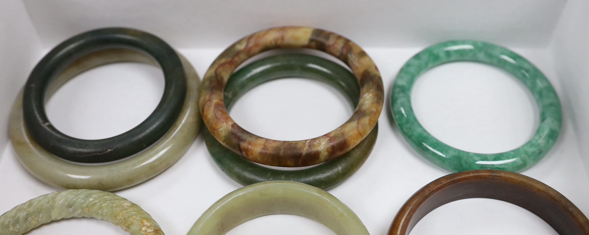 Eleven Chinese jade or hardstone bangles, largest 9cm